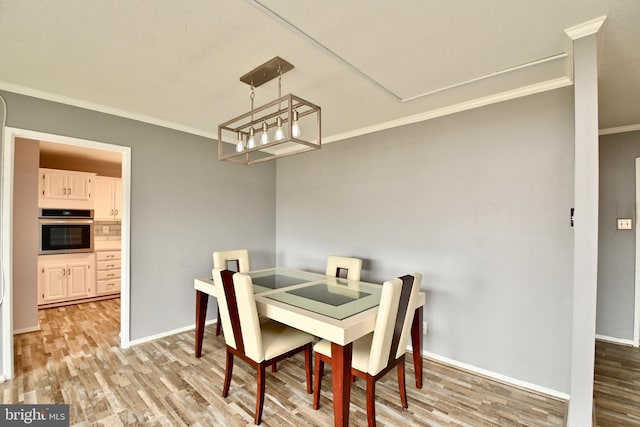 dining area featuring crown molding, baseboards, and wood finished floors