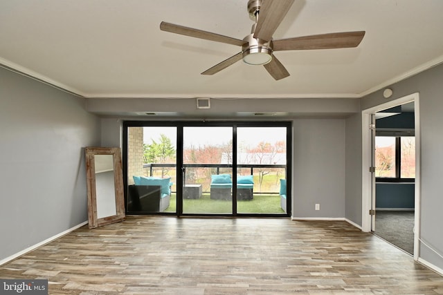 empty room featuring light wood-type flooring, visible vents, crown molding, and baseboards