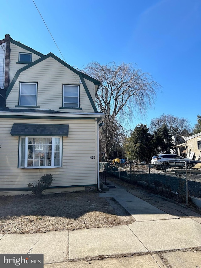 view of property exterior with fence and a gambrel roof