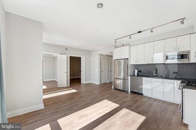 kitchen featuring stainless steel appliances, dark wood-style flooring, white cabinets, decorative backsplash, and dark countertops