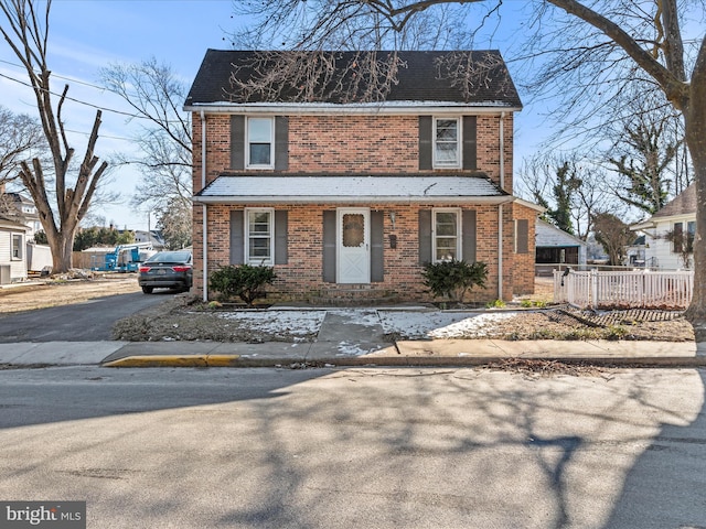 view of front of home featuring aphalt driveway, brick siding, and fence