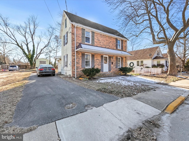 view of front of property featuring brick siding, driveway, and fence