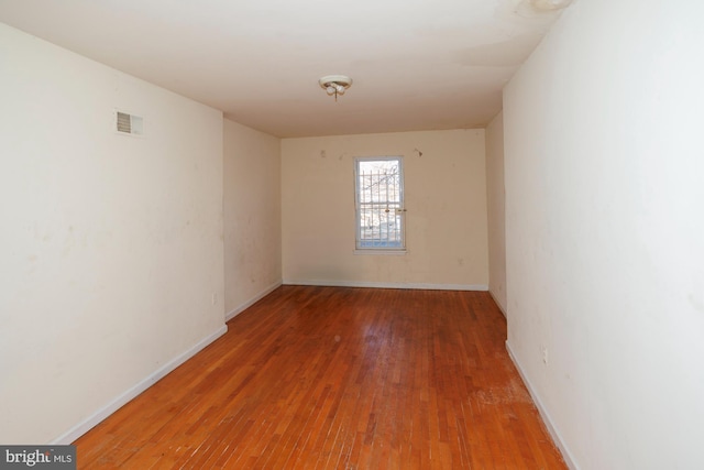 empty room with visible vents, baseboards, and wood finished floors