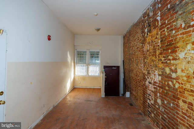 corridor featuring brick wall and wood finished floors