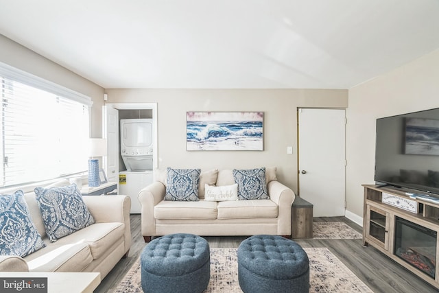 living room with stacked washer / drying machine and wood finished floors