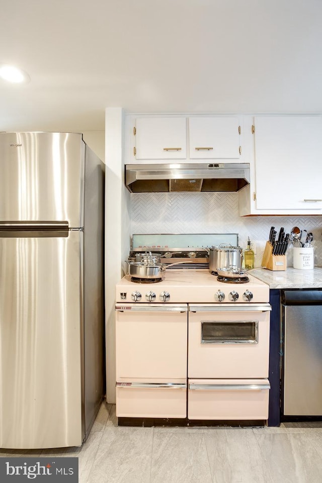 kitchen with freestanding refrigerator, double oven range, under cabinet range hood, and white cabinetry