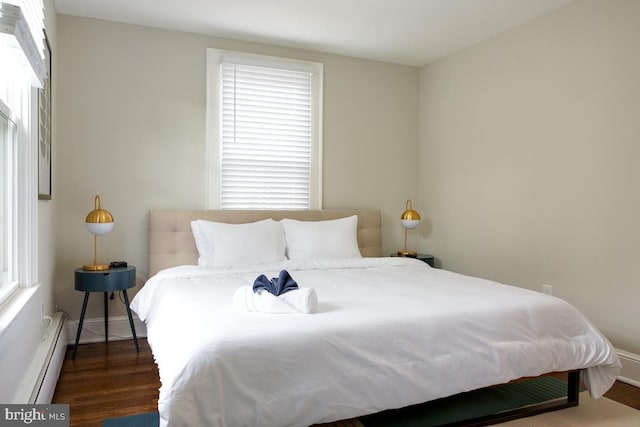 bedroom with a baseboard radiator, dark wood-style flooring, and baseboards