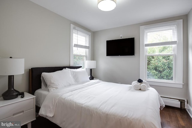 bedroom featuring a baseboard heating unit, multiple windows, and dark wood-style floors