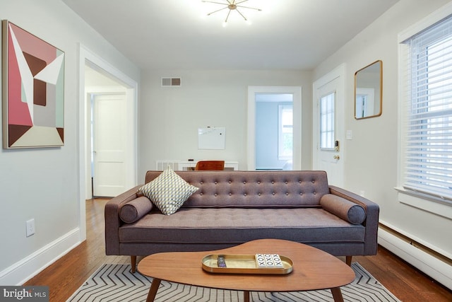 living area with a wealth of natural light, a baseboard radiator, visible vents, and wood finished floors