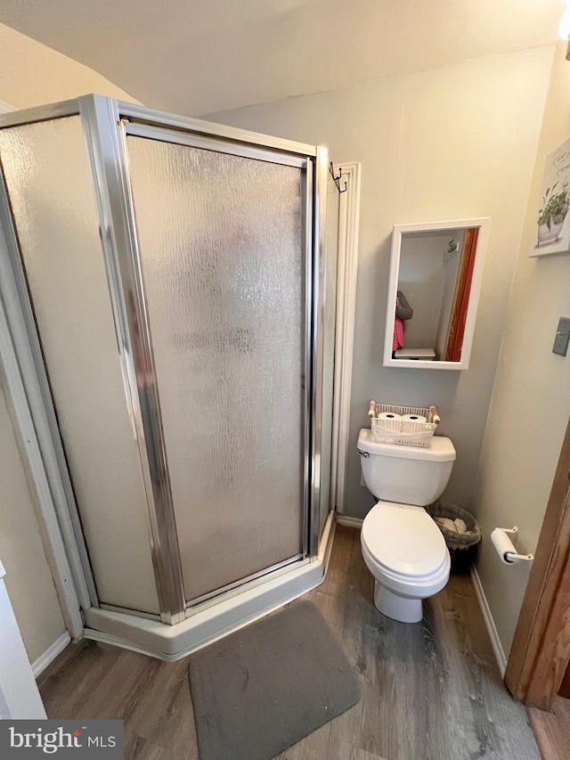 full bathroom with a stall shower, wood finished floors, toilet, and baseboards