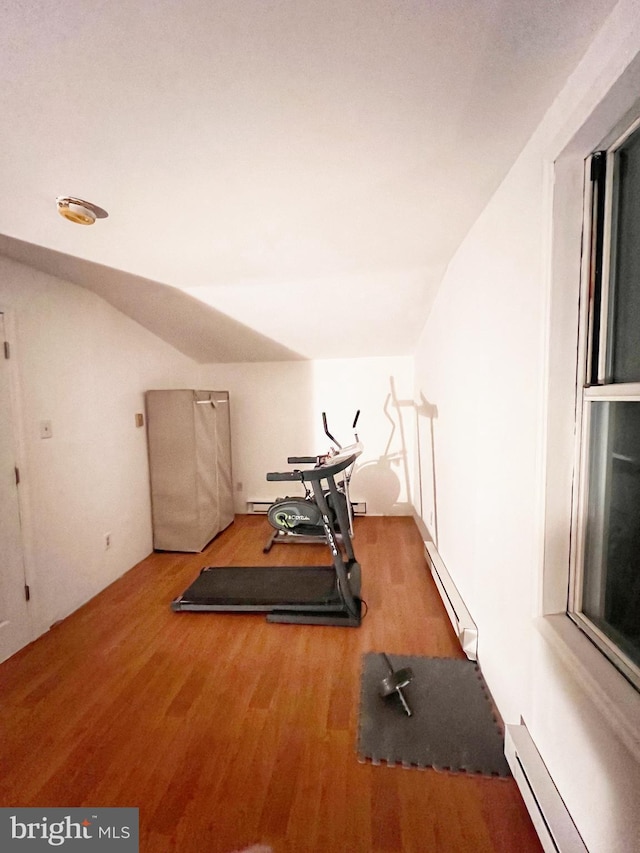 workout room featuring a baseboard radiator, lofted ceiling, and wood finished floors