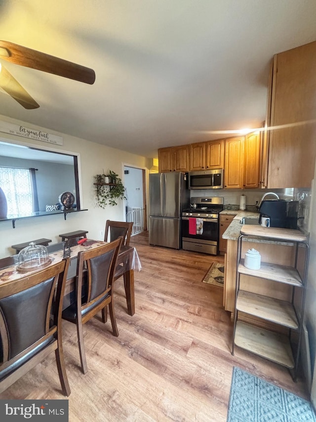 kitchen with brown cabinetry, light wood-style floors, stainless steel appliances, and light countertops