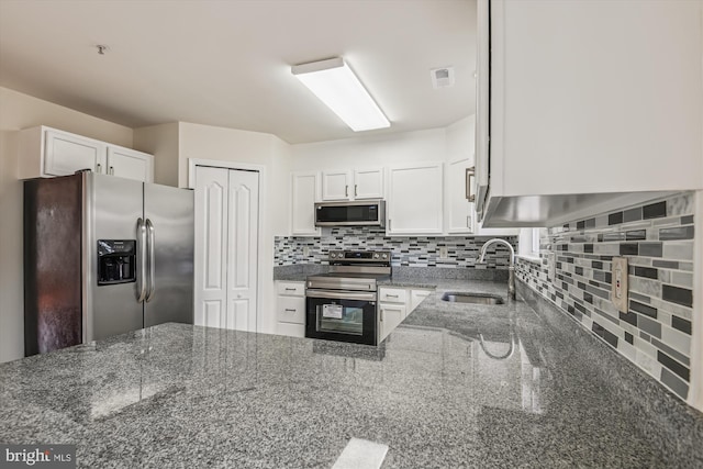 kitchen with appliances with stainless steel finishes, white cabinets, and dark stone countertops