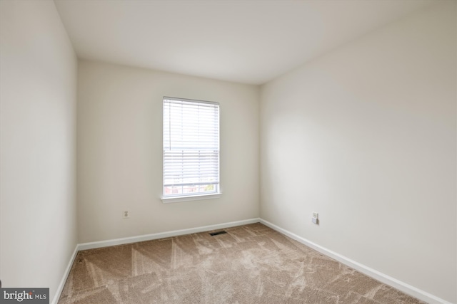 spare room featuring baseboards and light colored carpet