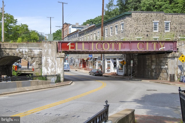 view of street with sidewalks, traffic signs, street lights, and curbs