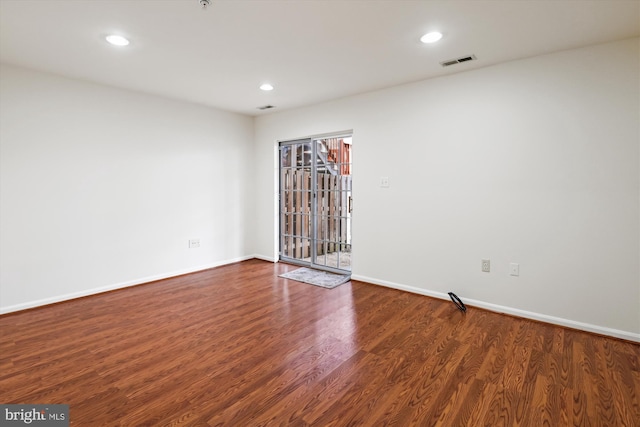 empty room with baseboards, visible vents, dark wood-type flooring, and recessed lighting