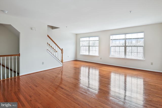 unfurnished living room with baseboards, stairway, and light wood-style floors