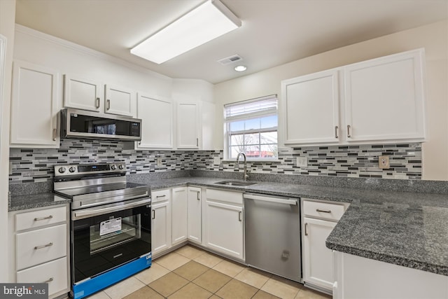 kitchen featuring stainless steel appliances, tasteful backsplash, visible vents, white cabinetry, and a sink