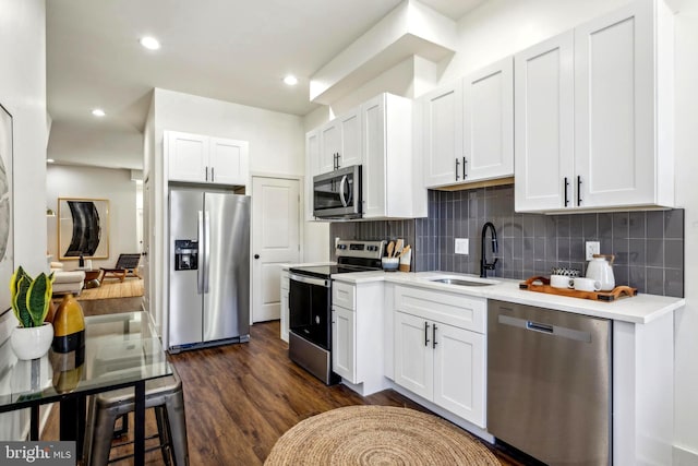 kitchen featuring white cabinetry, stainless steel appliances, a sink, and light countertops