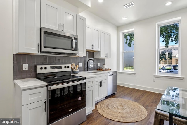 kitchen featuring a sink, visible vents, white cabinetry, appliances with stainless steel finishes, and decorative backsplash