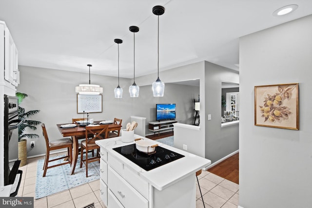 kitchen with a kitchen island, light countertops, light tile patterned flooring, white cabinets, and black appliances