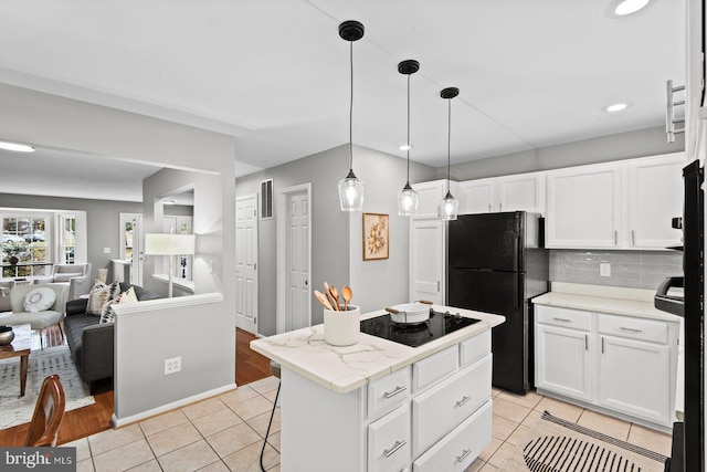 kitchen with light tile patterned floors, black appliances, white cabinetry, backsplash, and a center island