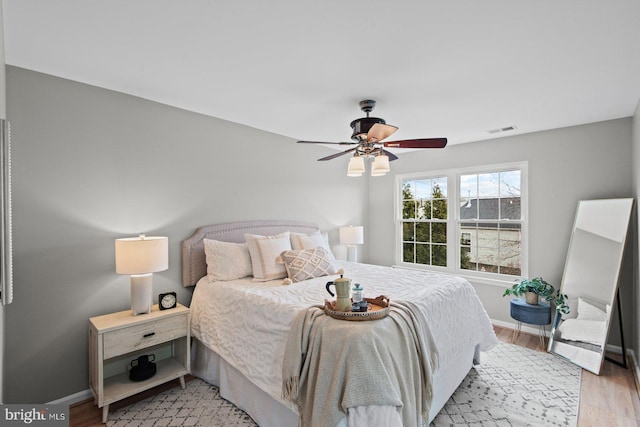 bedroom with light wood-type flooring, visible vents, baseboards, and ceiling fan