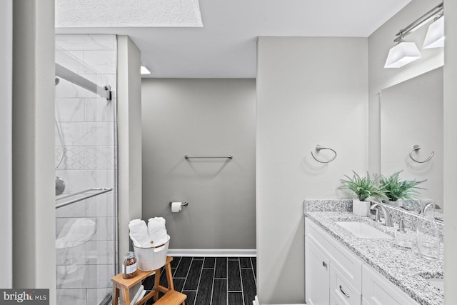 bathroom featuring wood finish floors, baseboards, a stall shower, and vanity