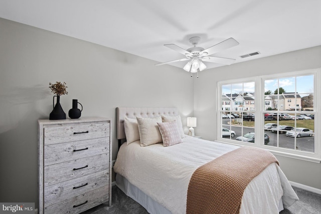 carpeted bedroom with visible vents, baseboards, and a ceiling fan