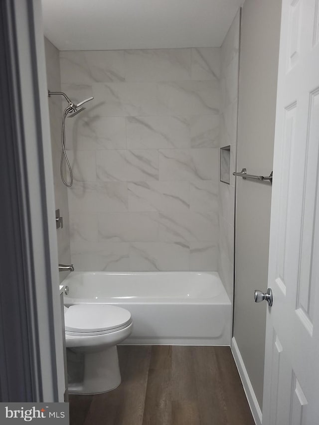 full bathroom with toilet, wood finished floors, baseboards, and shower / washtub combination