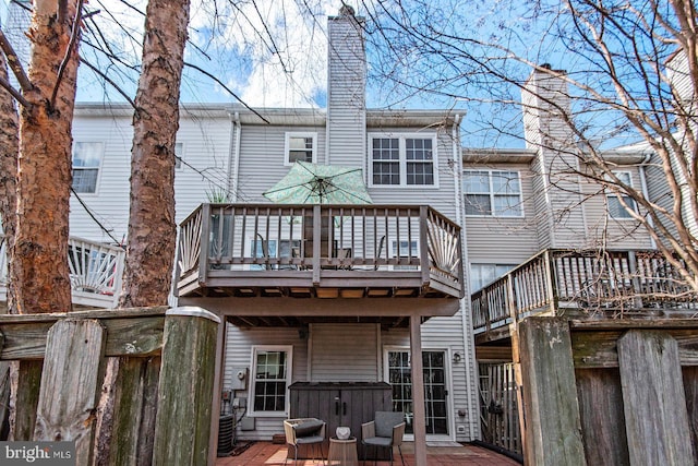 rear view of house with central AC unit, a deck, and a chimney