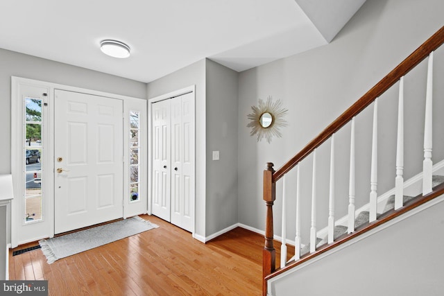 foyer entrance featuring stairway, wood-type flooring, and baseboards