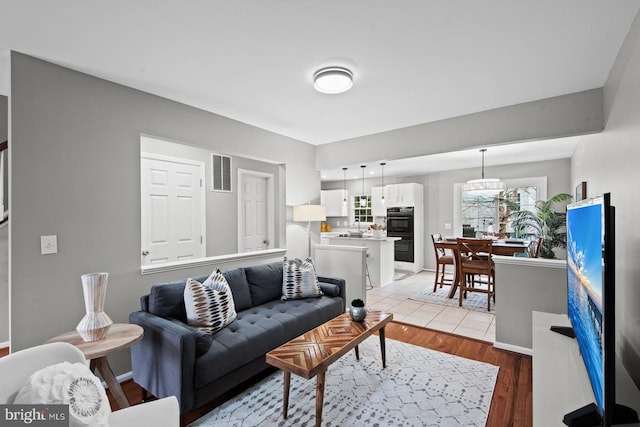 living area with baseboards, visible vents, and light wood finished floors