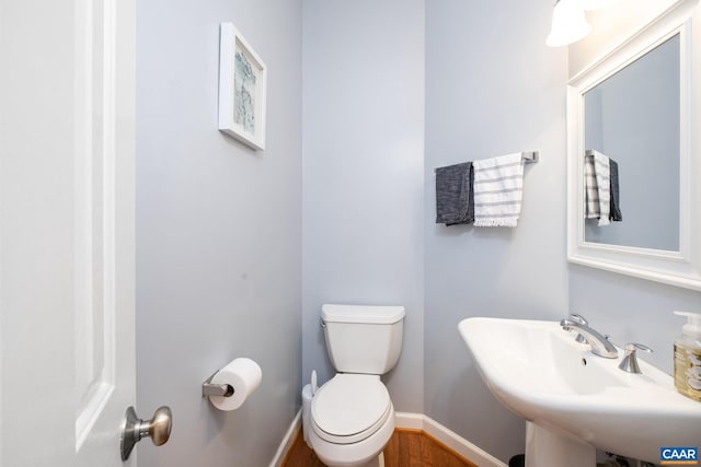 half bath featuring a sink, toilet, and baseboards