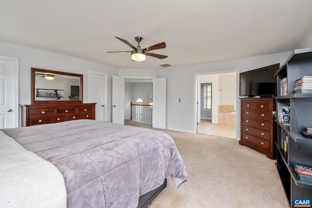 bedroom featuring visible vents, ensuite bathroom, a ceiling fan, light carpet, and baseboards