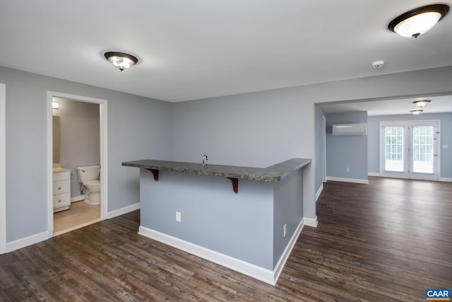 kitchen with dark wood-style flooring, a breakfast bar area, a wall mounted air conditioner, and baseboards