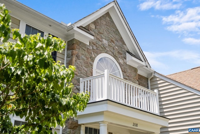 view of property exterior featuring stone siding and a balcony