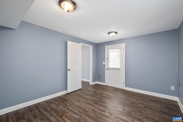 spare room featuring dark wood finished floors and baseboards