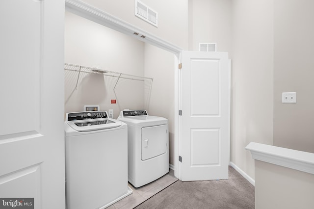 washroom with light colored carpet, laundry area, visible vents, and washer and clothes dryer