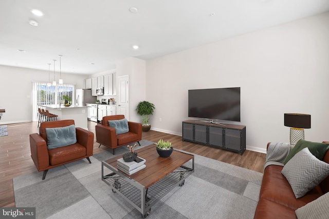 living area featuring baseboards, recessed lighting, and light wood-style floors