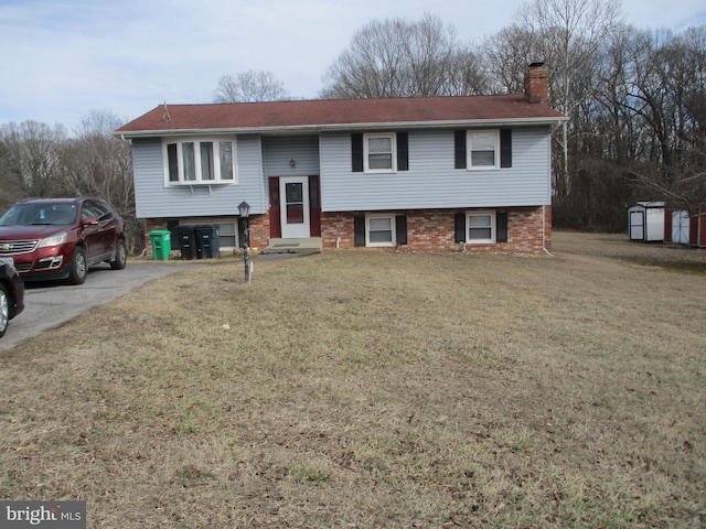 raised ranch featuring an outbuilding, a front lawn, driveway, a shed, and a chimney