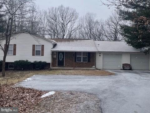 tri-level home featuring a garage, driveway, and brick siding