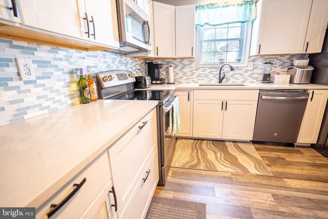 kitchen featuring decorative backsplash, appliances with stainless steel finishes, light countertops, and a sink