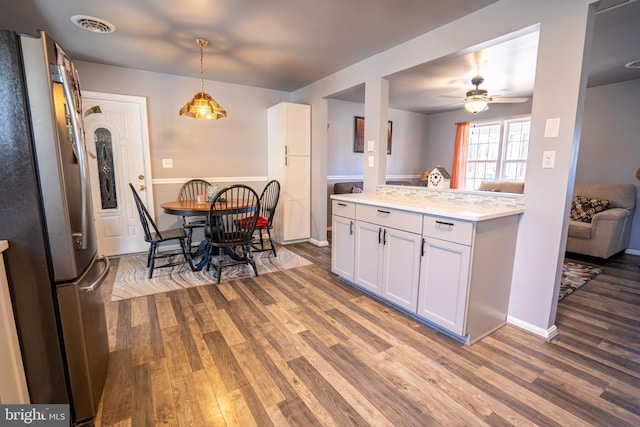 kitchen featuring visible vents, light countertops, wood finished floors, and freestanding refrigerator