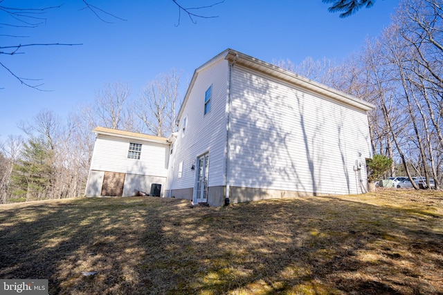 view of home's exterior with cooling unit and a lawn