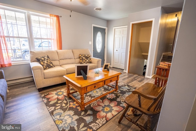 living room featuring a baseboard radiator, visible vents, plenty of natural light, and wood finished floors