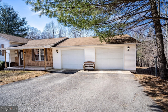 view of front of home featuring brick siding, a shingled roof, covered porch, an attached garage, and driveway