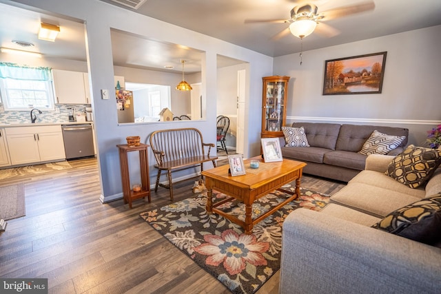 living room with ceiling fan, baseboards, and wood finished floors