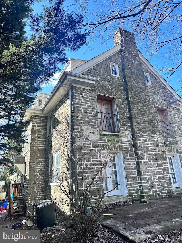 view of side of home featuring a chimney and a balcony