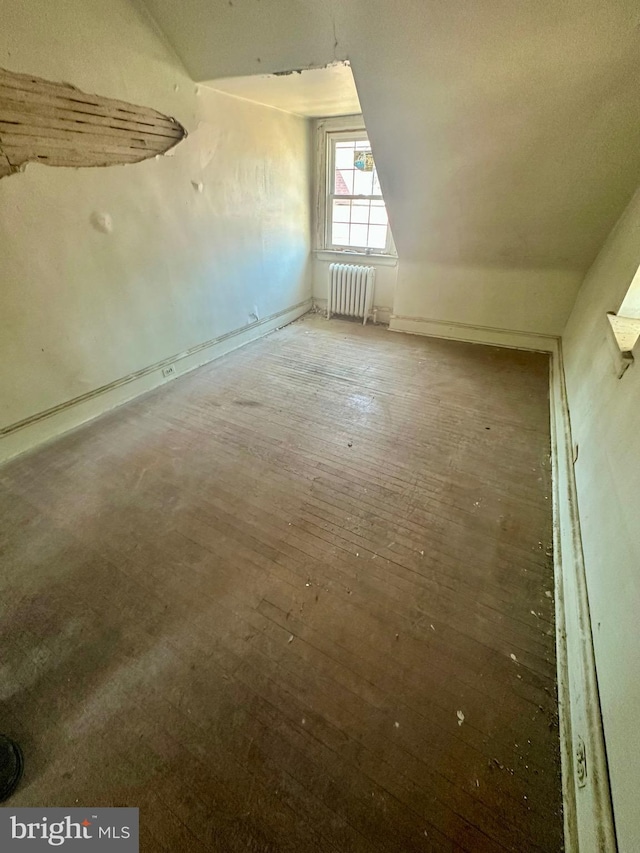 additional living space with lofted ceiling, radiator heating unit, and wood finished floors